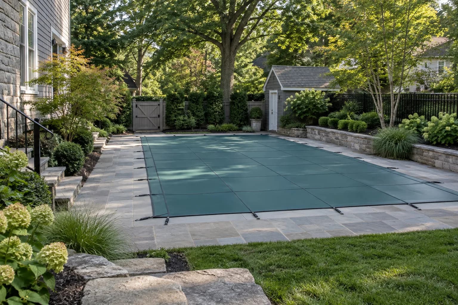 Northeast backyard pool concept with stone coping, deciduous trees, fitted cover, and compact access